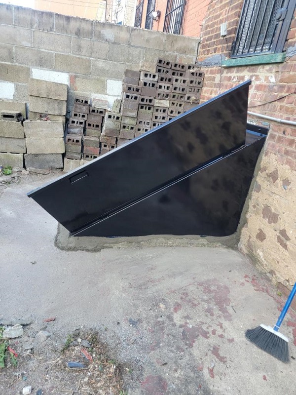 Open angled backyard bulkhead cellar door installation, painted black