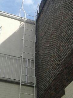 Simple steel fixed roof access ladder braced building widened Fabricated bolted installation positioning