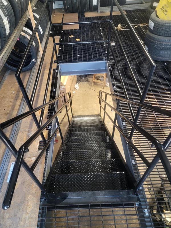 Welded pipe guard-railing around cut grating opening — Brooklyn interior staircase