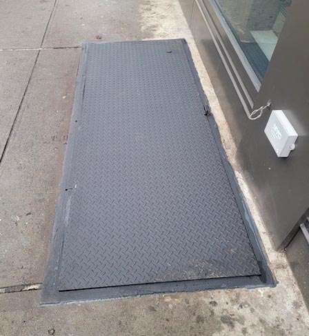 Oversized single leaf diamond plate sidewalk door over staircases