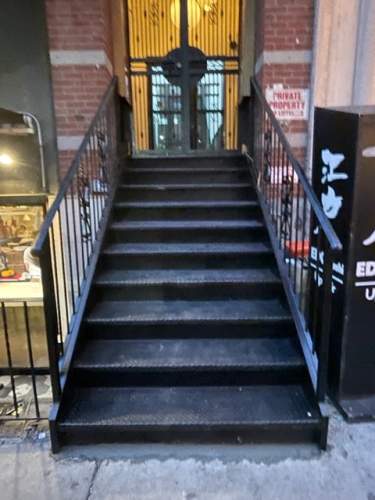 Outside closed treaded diamond plate steps railings double doors, lower east side, NYC